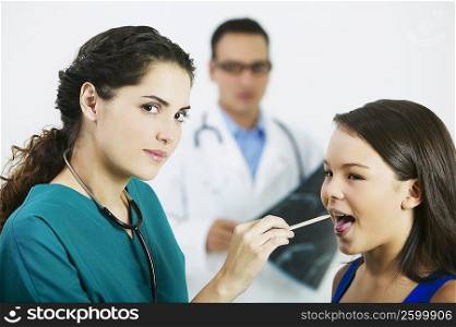 Side profile of a female doctor examining a girl&acute;s mouth with a tongue depressor