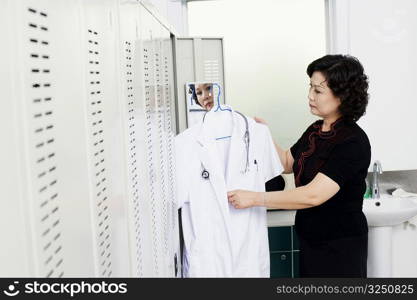 Side profile of a female doctor holding a lab coat