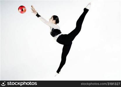 Side profile of a female gymnast practicing with a ball