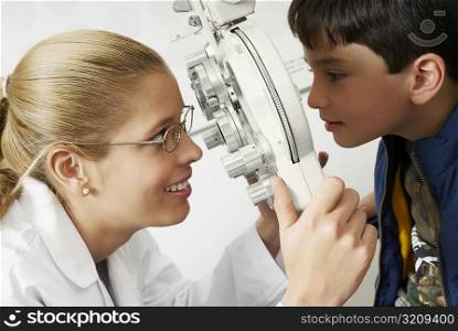 Side profile of a female optometrist examining a boy&acute;s eye