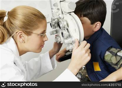 Side profile of a female optometrist examining a boy&acute;s eye