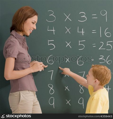 Side profile of a female teacher teaching her student on a blackboard