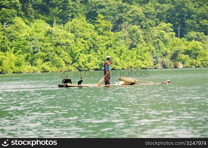 Side profile of a fisherman standing on a bamboo raft in a river, XingPing, Yangshuo, Guangxi Province, China