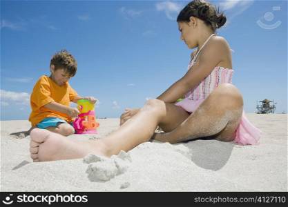 Side profile of a girl and a boy playing on the beach