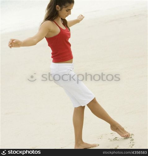 Side profile of a girl drawing in the sand with her toe