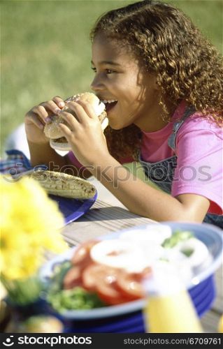 Side profile of a girl eating a hamburger