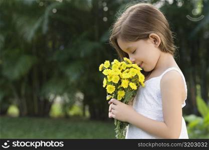 Side profile of a girl holding a bunch of flowers and smelling