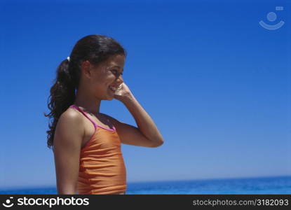 Side profile of a girl holding a conch to her ear