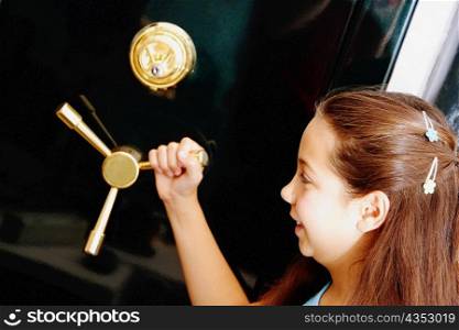 Side profile of a girl holding the handle of a safe