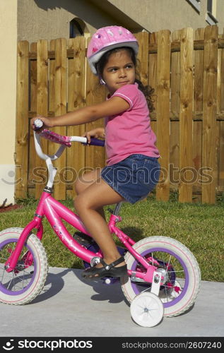 Side profile of a girl riding a bicycle on a path