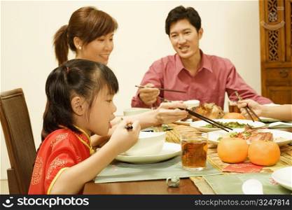 Side profile of a girl sitting at the dining table with her parents