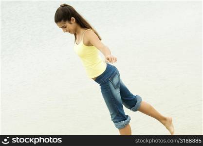 Side profile of a girl standing on one leg on the beach