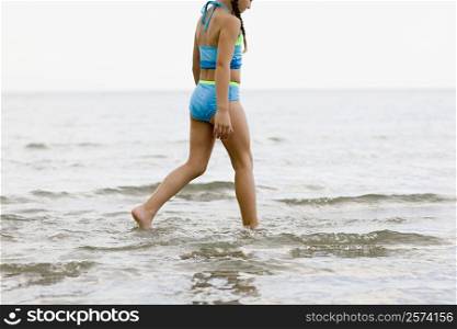 Side profile of a girl wading in water on the beach
