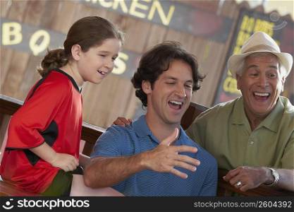 Side profile of a girl with her father and grandfather sitting in a restaurant