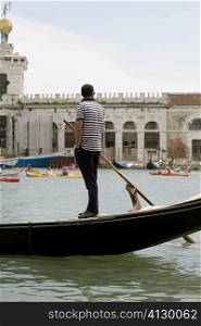 Side profile of a gondolier standing on a gondola, Venice, Veneto, Italy