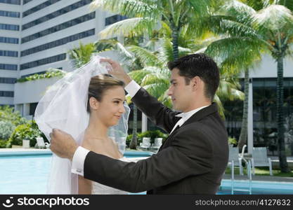 Side profile of a groom lifting his bride&acute;s veil