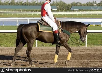 Side profile of a jockey riding a horse on a horseracing track