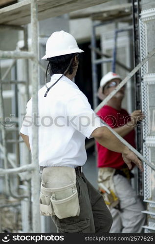 Side profile of a male architect working at a construction site with another male architect standing beside him