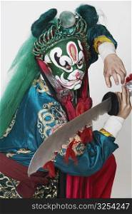Side profile of a male Chinese opera performer holding a weapon