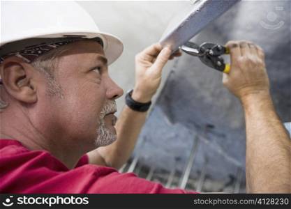 Side profile of a male construction worker working with a wrench