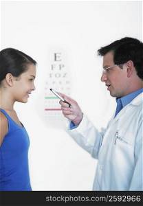 Side profile of a male doctor doing an eye exam of a female patient