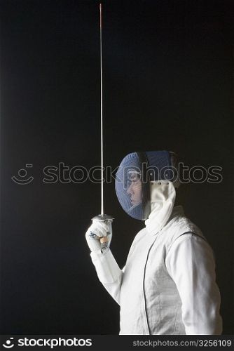 Side profile of a male fencer holding a fencing foil