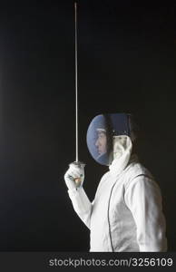 Side profile of a male fencer holding a fencing foil