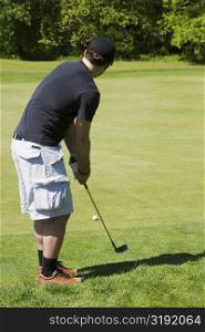 Side profile of a man holding a golf club on a golf course