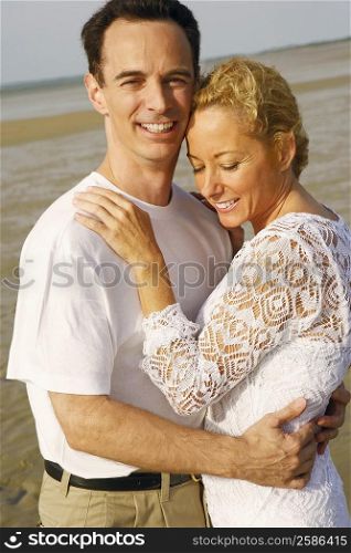 Side profile of a mature couple embracing each other on the beach