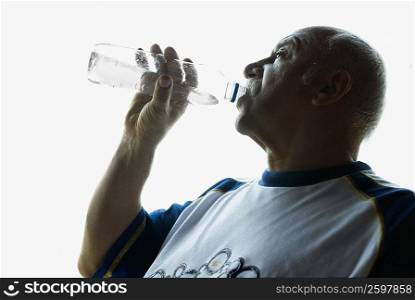 Side profile of a mature man drinking water from a bottle