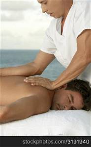 Side profile of a mature man giving a mid adult man a back massage