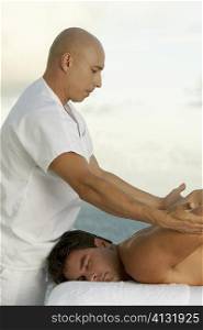 Side profile of a mature man giving a mid adult man a back massage