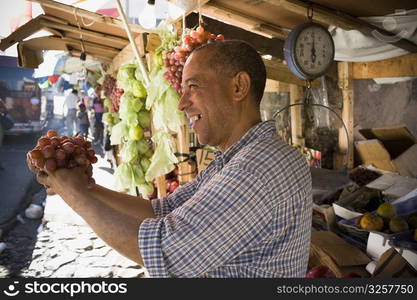 Side profile of a mature man holding a bunch of red grapes, Santo Domingo, Dominican Republic