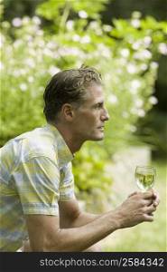 Side profile of a mature man holding a glass of wine and thinking