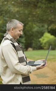 Side profile of a mature man holding a laptop and smiling