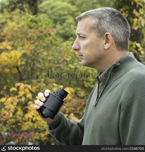 Side profile of a mature man holding binoculars