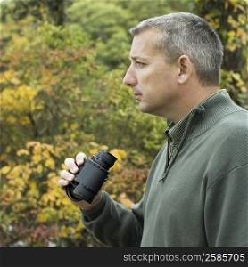Side profile of a mature man holding binoculars