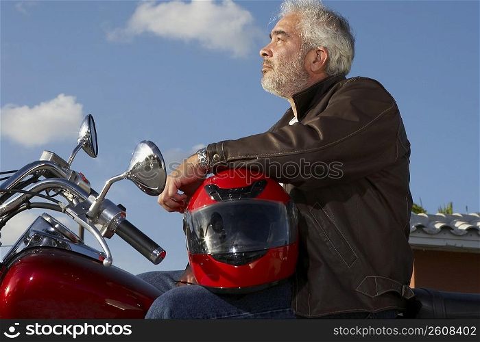 Side profile of a mature man sitting on a motorcycle