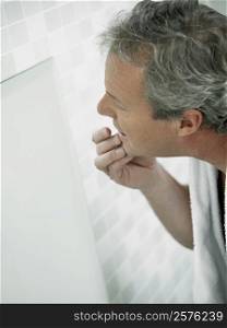 Side profile of a mature man touching his face in a mirror