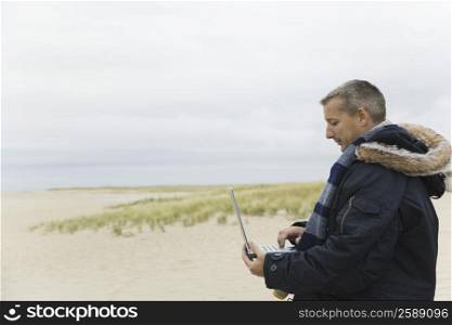Side profile of a mature man using a laptop on the beach
