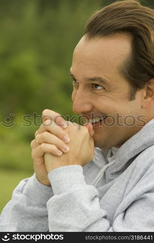 Side profile of a mature man with his hands clasped