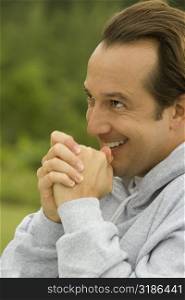 Side profile of a mature man with his hands clasped