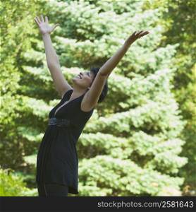 Side profile of a mature woman cheering with her arm outstretched in a park