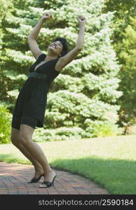 Side profile of a mature woman cheering with her arm outstretched in a park
