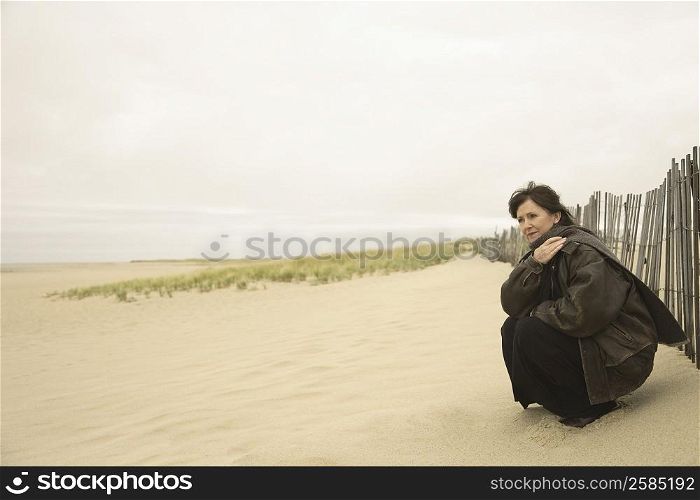 Side profile of a mature woman crouching on the beach