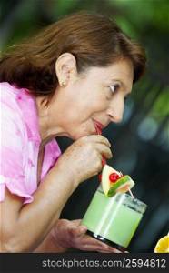 Side profile of a mature woman drinking juice