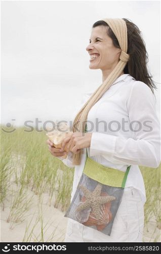 Side profile of a mature woman holding a conch shell and smiling