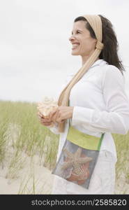 Side profile of a mature woman holding a conch shell and smiling