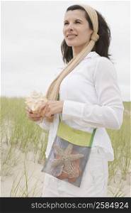 Side profile of a mature woman holding a conch shell and thinking