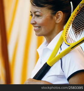 Side profile of a mature woman holding a tennis racket and smiling